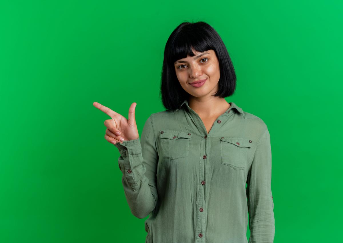 pleased-young-brunette-caucasian-woman-points-side-isolated-green-background-with-copy-space.jpg